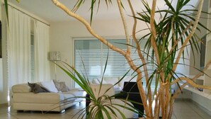 Een moderne woonkamer met een grote potplant, een bank en een vloerlamp.
