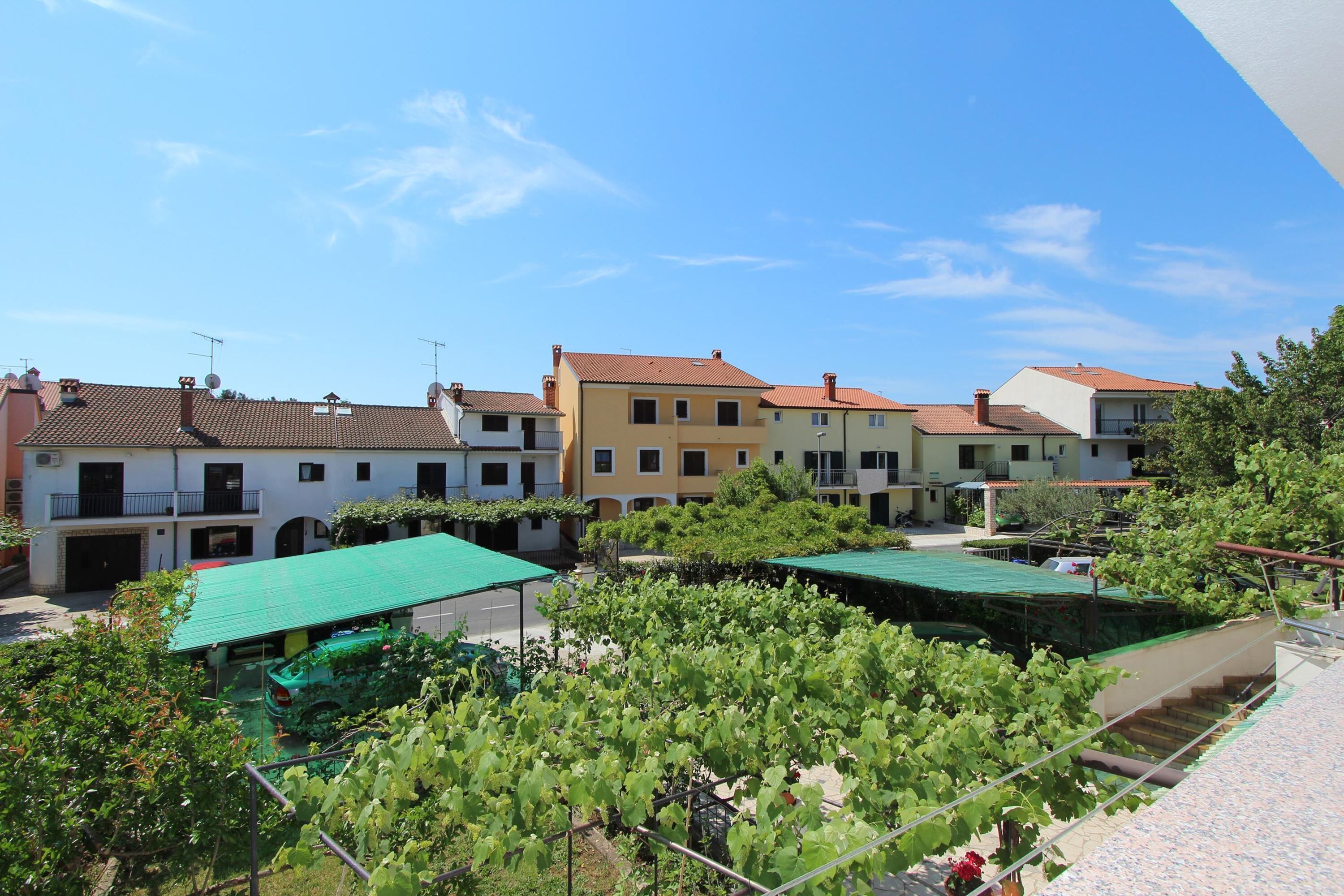 Un quartier résidentiel avec des immeubles à plusieurs étages, une voiture verte et des vignes.