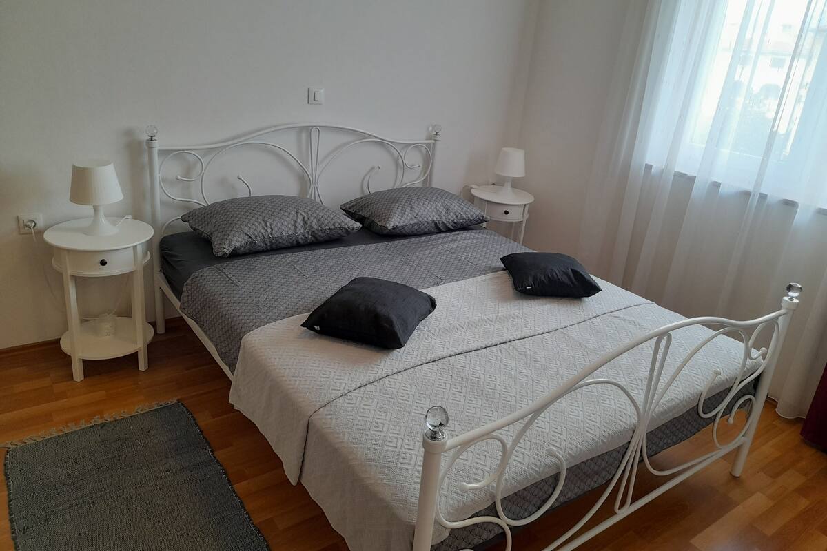 Une chambre à coucher bien rangée, avec un lit, deux tables de chevet et une petite table d’appoint.