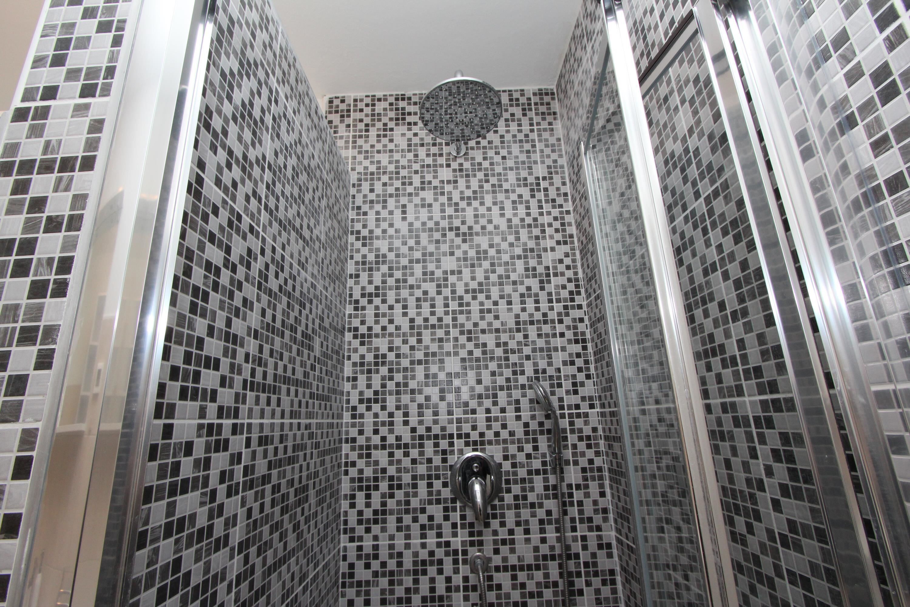 A bathroom with a tiled mosaic wall and a shower area.