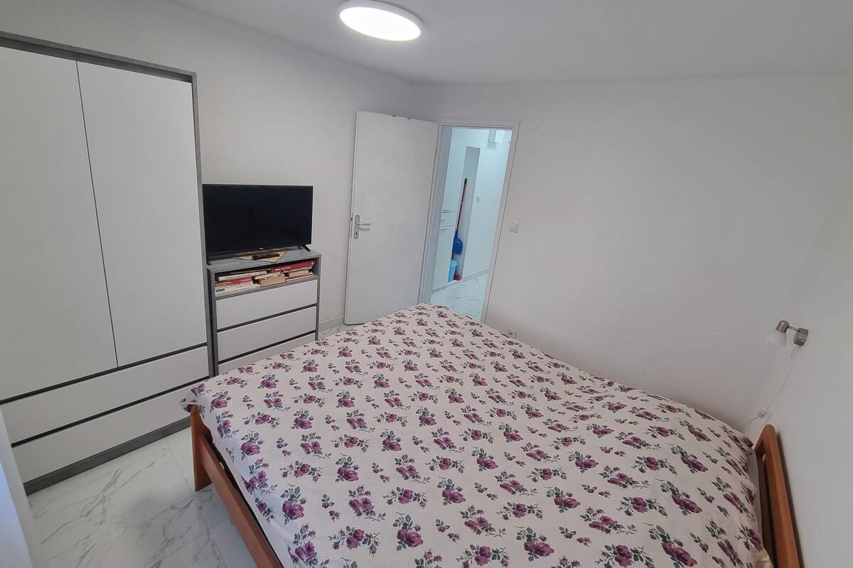 Une chambre à coucher avec un lit, une armoire et un téléviseur posé sur un meuble.