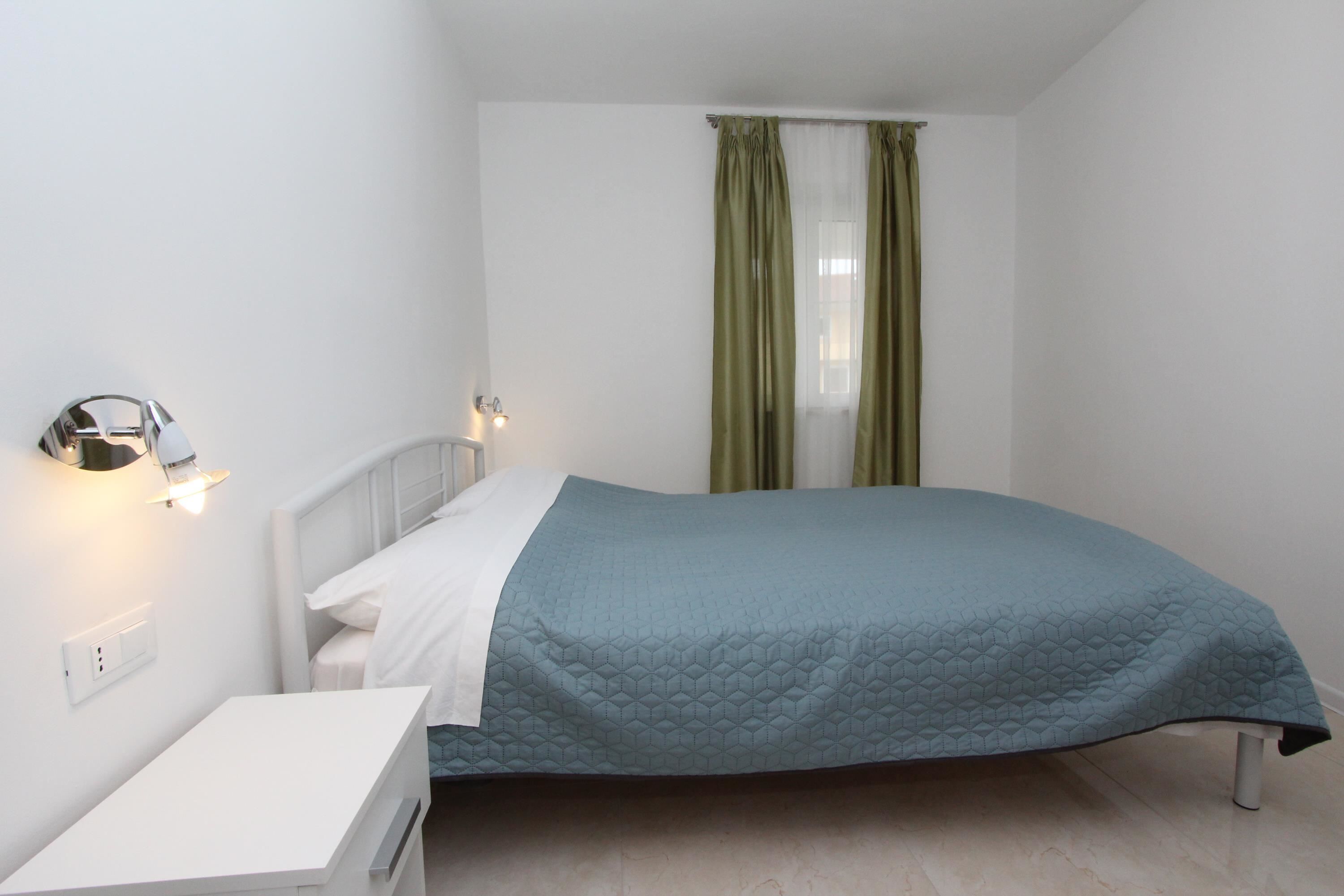 A bedroom with a bed, bedside table, and a wall-mounted light fixture.