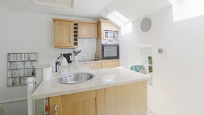 Een moderne keuken met houten kastjes, een roestvrijstalen spoelbak, een magnetron en een oven.