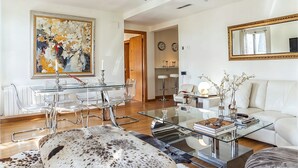 A modern living room with a glass coffee table, white sofa, and a large abstract painting. - Exquisite designer 3BR Pg Gràcia apt - LaMimosa (Barcelona)