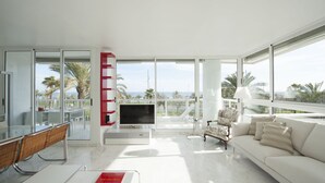 Ein geräumiges Wohnzimmer mit einem weißen Sofa, einem Fernseher und einem Essbereich mit Stühlen und einem Tisch.
