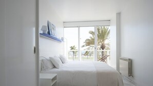 Ein Schlafzimmer mit einem großen Bett, einem Nachttisch, einem Fenster mit Blick auf Palmen und einer Heizung.