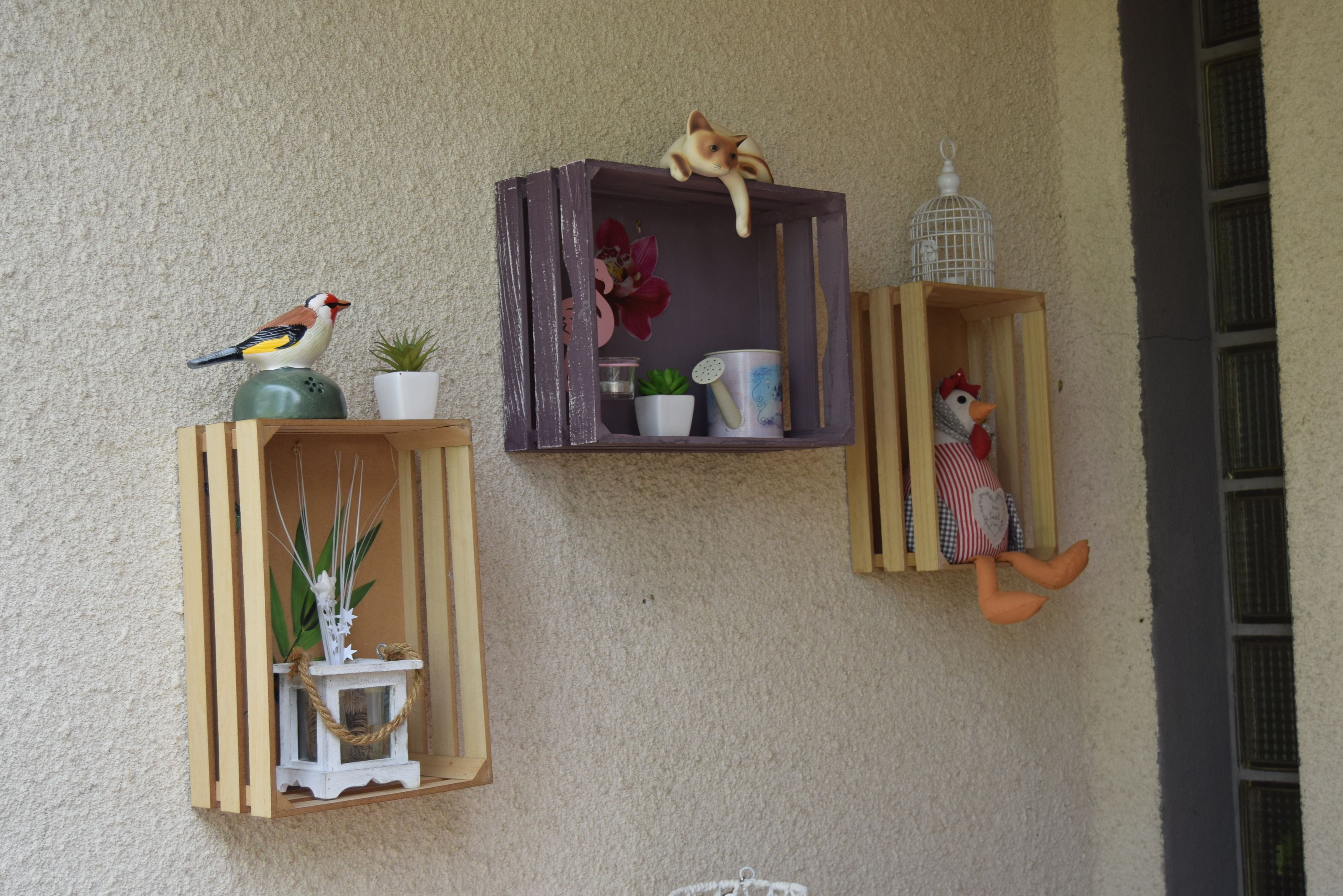 Trois étagères fixées au mur, ornées de divers objets décoratifs, notamment des figurines, un oiseau et une plante.