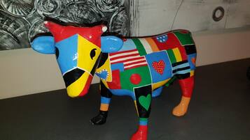 A colorful, abstract sculpture of a cow on a dark floor.