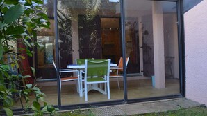 Une maison moderne dotée d’une porte coulissante en verre qui donne sur un espace repas extérieur, avec une table et des chaises.