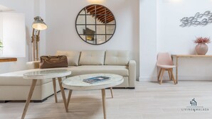 Una sala de estar moderna con un espejo redondo, un sofá, una mesa de centro, una lámpara y un adorno de pared.