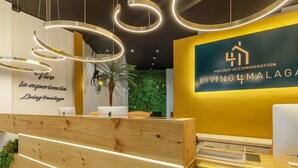 Un mostrador de recepción con detalles de madera, una pared verde con una planta y un letrero que dice 'Holiday Accommodation Living Himalaya'.