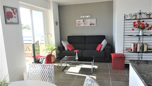 A living room with a black sofa, a coffee table, and a bookshelf. - Playa d'Aro,2 bedrooms, 2 bathrooms, sea view, air conditioning, large terrace, free wifi, private parking (Platja d'Aro)