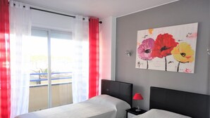 A hotel room with two beds, a red lamp, and a painting of flowers on the wall. - Playa d'Aro,2 bedrooms, 2 bathrooms, sea view, air conditioning, large terrace, free wifi, private parking (Platja d'Aro)
