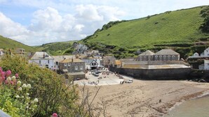 Eine Küstenstadt mit historischen Gebäuden, einem Sandstrand und einer Hügelkulisse im Hintergrund.