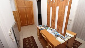 A room with a wooden wardrobe, a wooden desk with magazines, and a patterned rug. - Studio Pupa (Rovinj)