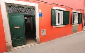 Un edificio con una puerta verde y ventanas con contraventanas verdes. Una señal en la pared indica que se trata de un estudio.