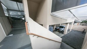 A staircase with a handrail leading to a covered outdoor area. - Bruno Henning - Apto 6 pessoas (Itapema)