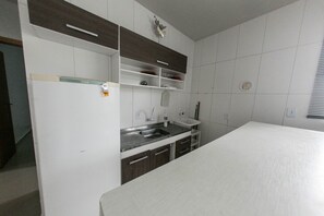A modern kitchen with white cabinets, a stainless steel sink, and a white countertop.
