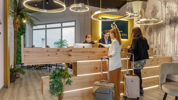 Ein moderner Empfangstresen mit Holzoptik, eine große Schreibtischlampe und ein Schild mit der Aufschrift 'LAGA'.