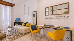 Ein modernes Wohnzimmer mit einer Couch, gelben Sessel, einem Esstisch und einem großen Spiegel.
