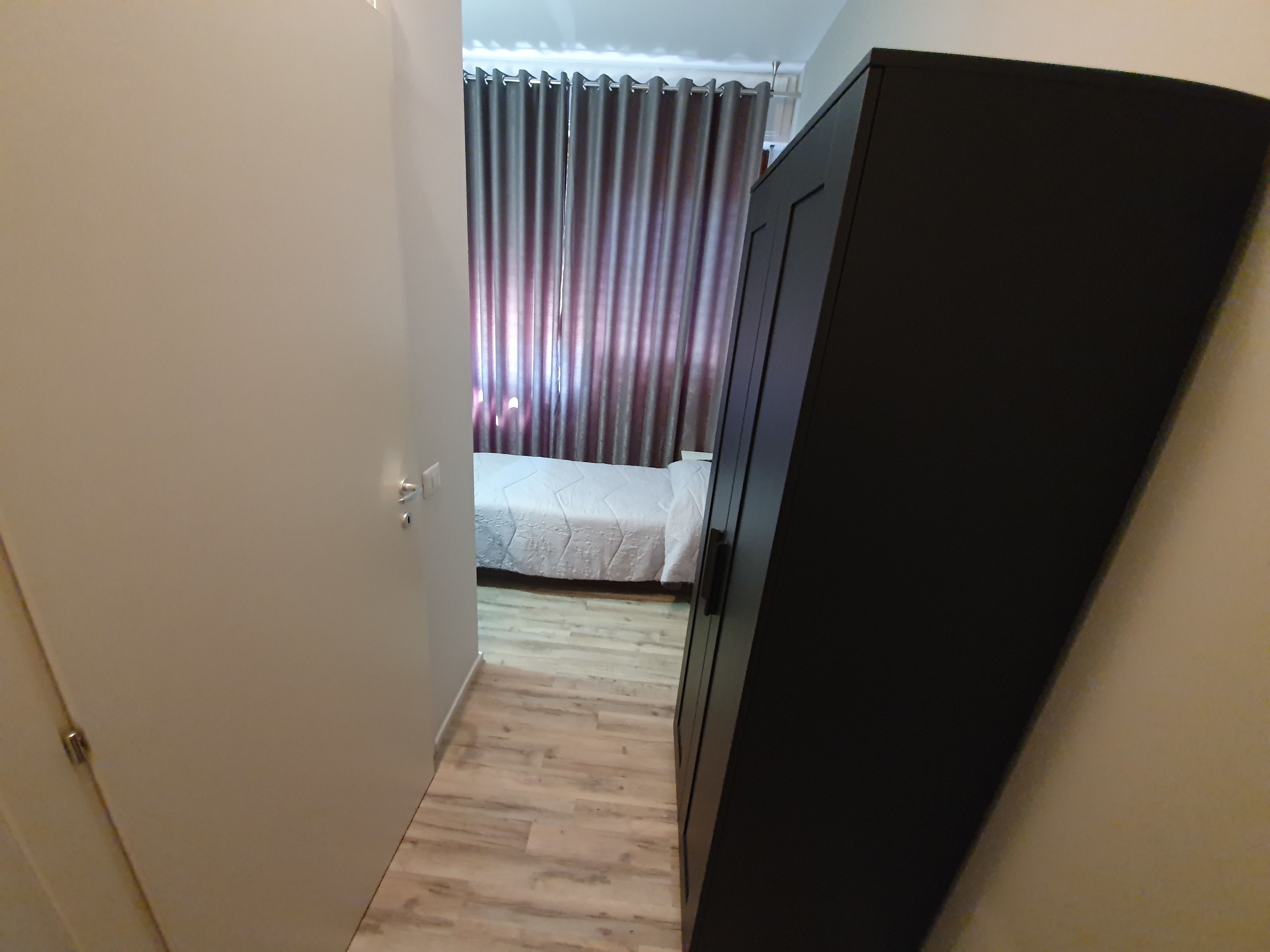 Ein schmaler Flur mit einem Bett und einem Kleiderschrank in einem Zimmer.