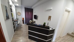 A modern hotel lobby with a reception desk, a clock, and a television on the wall. - Affittacamere Umberto I (Foligno)