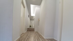 A narrow hallway with wooden flooring and white walls, leading to a staircase. - Affittacamere Umberto I (Foligno)