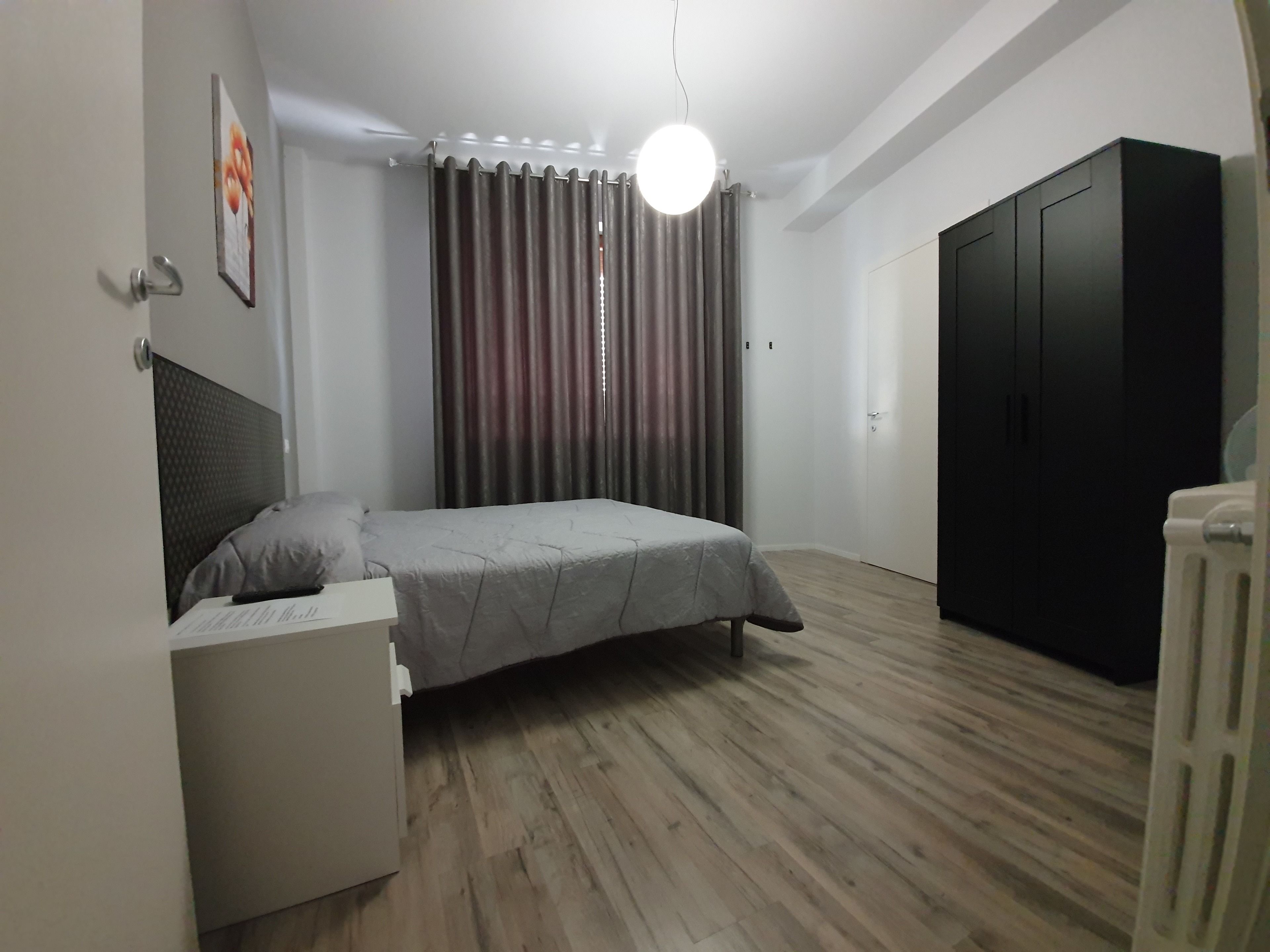 Une chambre à coucher comprenant un lit, une table de chevet, une armoire et un radiateur.