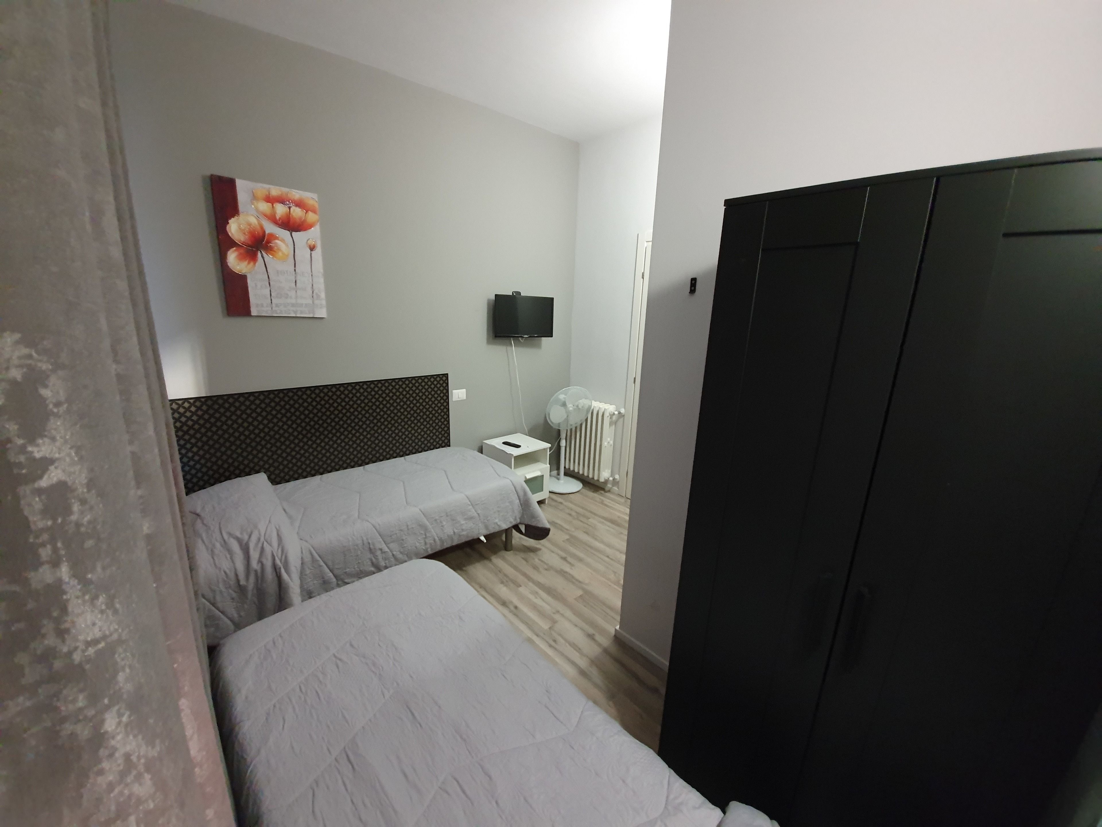 Une chambre d’hôtel avec deux lits simples, un téléviseur à écran plat, un radiateur et une armoire.
