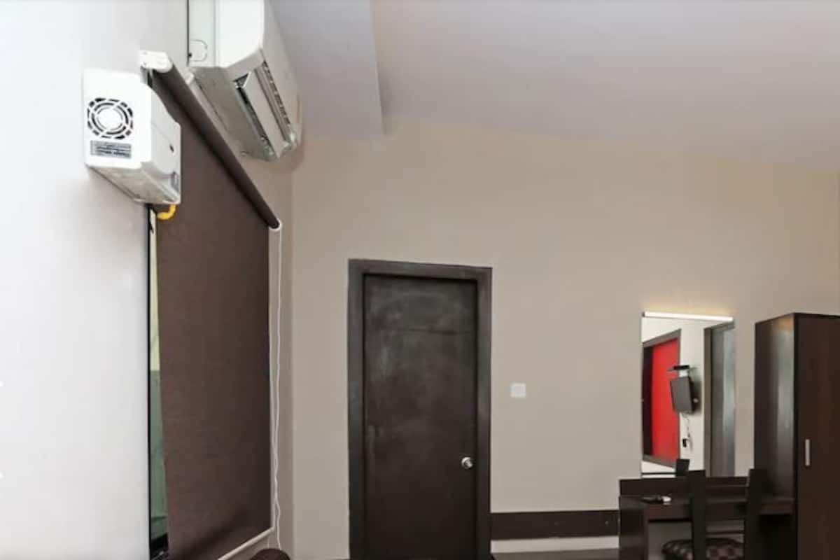 Un couloir avec deux portes, un miroir et un petit bureau avec une chaise.