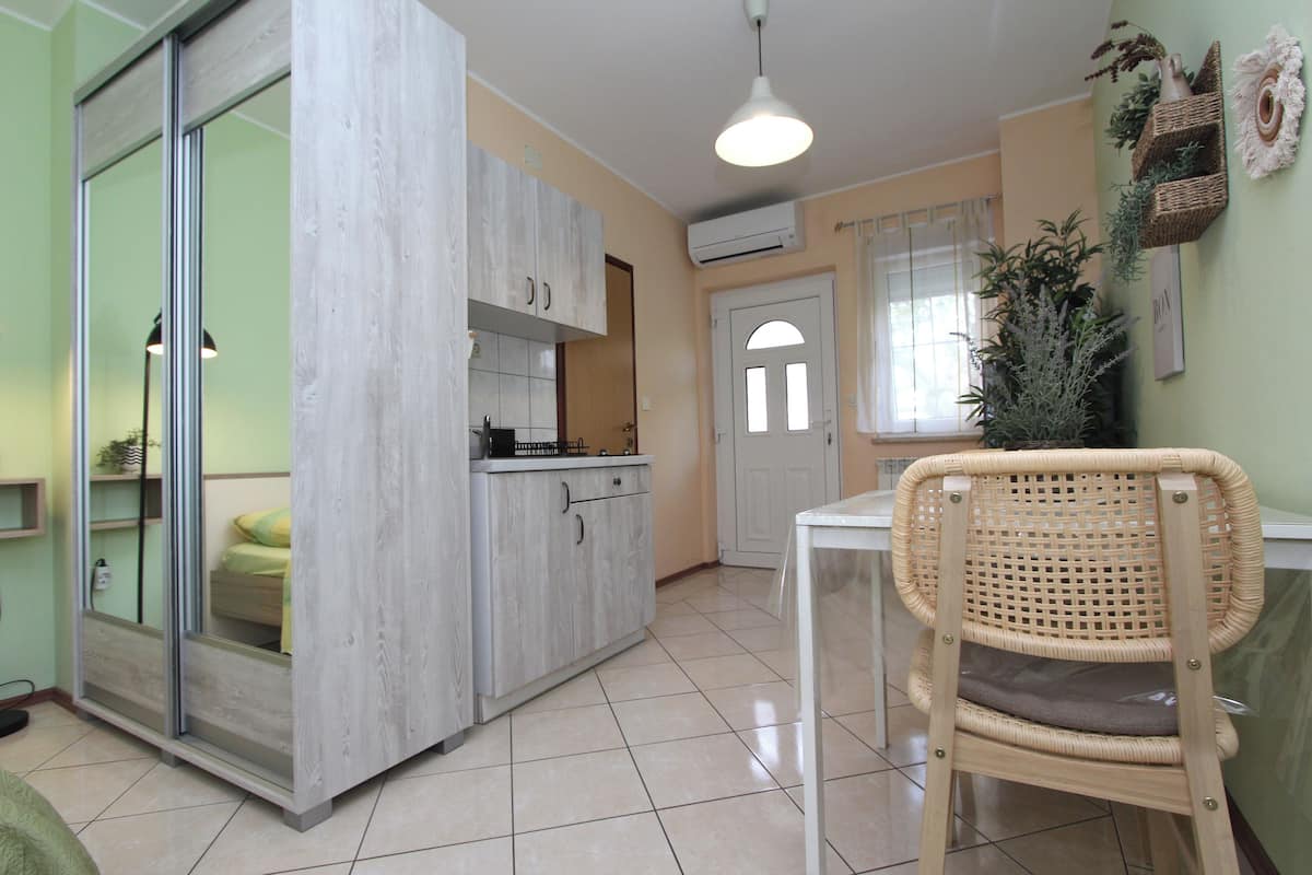 Una cocina compacta con comedor, una silla de mimbre y una pequeña mesa.