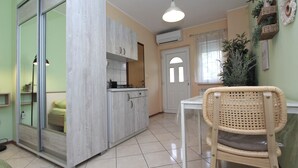 A compact kitchen with a dining area, a wicker chair, and a small table.