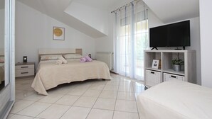 A bedroom with a bed, a TV, a nightstand, and a window with curtains.