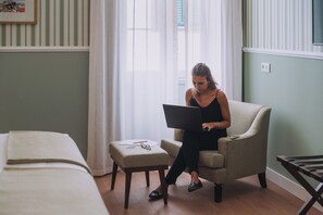 A room with a bed, a chair, and a table with a laptop.