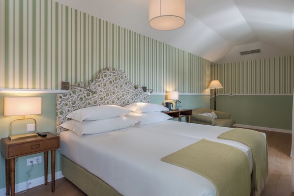 A hotel room with a large bed, two bedside tables, a nightstand, a lamp, a sofa, and a patterned headboard. - Pestana Churchill Bay (Camara de Lobos)
