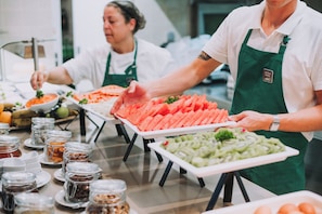 Montaje de bufé con diversos alimentos y personal de servicio.