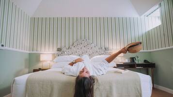 Een kamer met een bed, nachtkastje, lamp en raam.