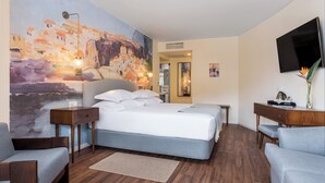 Une chambre d’hôtel moderne, dotée d’un grand lit, d’un bureau, d’une chaise, d’une télévision et d’un tableau au mur.