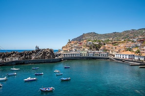 Un pueblo costero con edificios a lo largo del malecón, barcos en el agua y una costa rocosa.