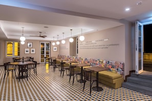 Ein modernes Restaurant-Interieur mit einem Schachbrettfußboden, mehreren Tischen und Stühlen, einer Couch und einer Wand mit Text.