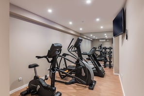 Une salle de sport équipée de vélos d’appartement, de tapis de course et d’un mur recouvert de miroirs.