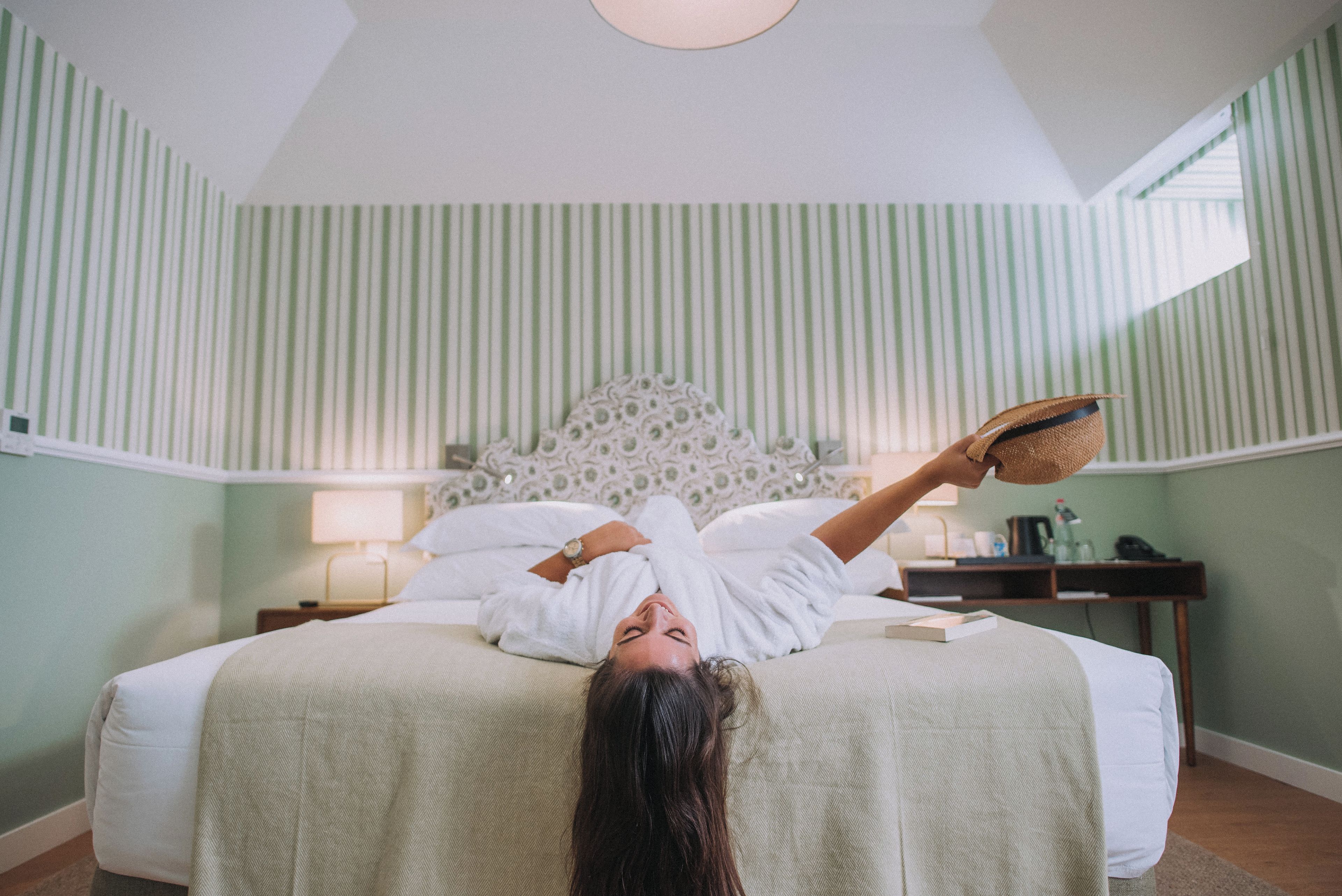 Une pièce comprenant un lit, une table de chevet, une lampe et une fenêtre.