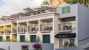 A hotel with multiple balconies, outdoor seating, and a sign for a restaurant.