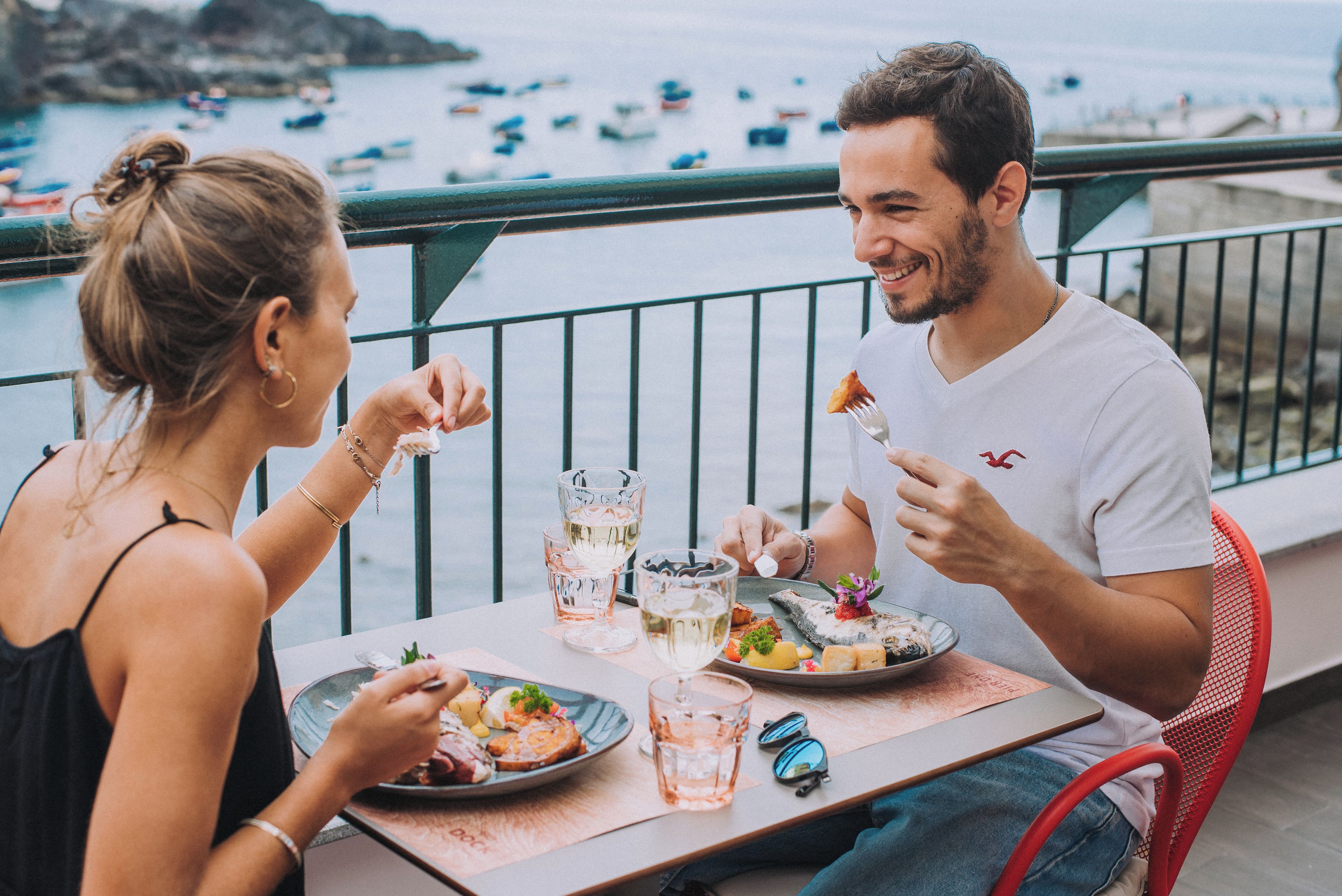 A couple dining at a table with a view of boats on the water.