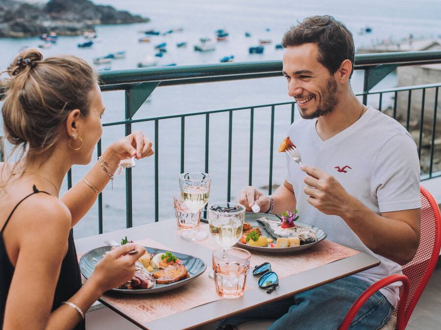 A couple dining at a table with a view of boats on the water.