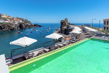 Una piscina al aire libre, sombrillas, sillones reclinables de piscina