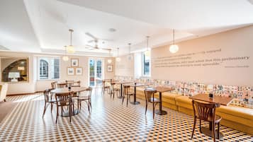 A modern dining area with a patterned floor, wooden furniture, and a wall with framed pictures and a quote.