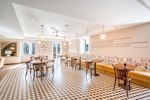 A modern dining area with a patterned floor, wooden furniture, and a wall with framed pictures and a quote.