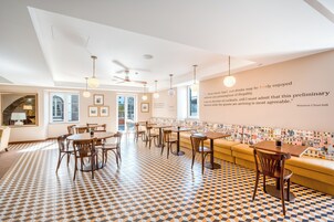 Un espace repas moderne avec un sol à motifs, des meubles en bois et un mur orné de tableaux et d’une citation.