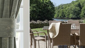Un patio con mobiliario de mimbre y vista al lago.